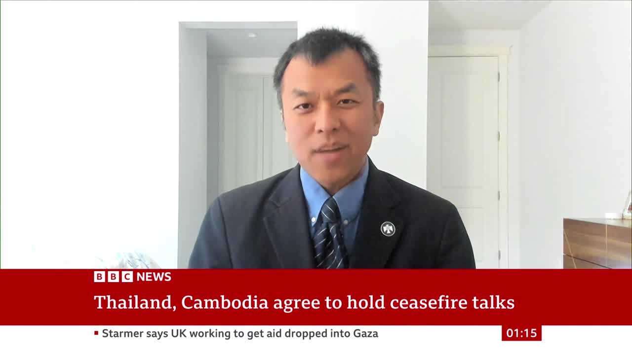 A man in a suit is speaking directly to the camera, likely on BBC News. The lower third of the screen displays a headline about ceasefire talks between Thailand and Cambodia.
