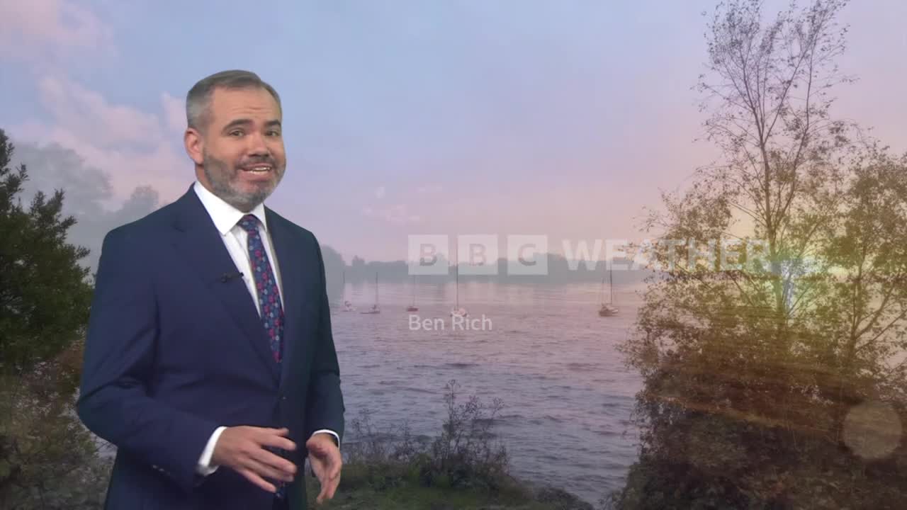 Standing here, Ben Rich from BBC Weather is delivering the forecast, with a serene lake scene behind him. The light is soft, and a few sailboats are visible on the water.
