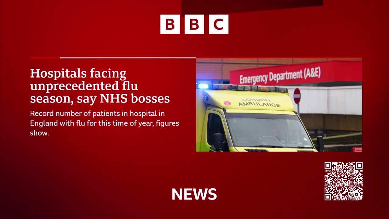 A London Ambulance is parked outside the Emergency Department, its blue lights flashing. The BBC News graphic highlights a story about hospitals in England facing an unprecedented flu season.

