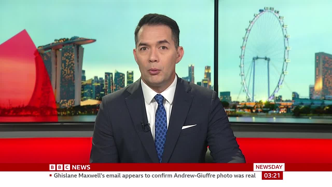 A man in a suit and tie speaks directly to the camera, his expression serious. Behind him, a news graphic displays the BBC News logo and a scrolling headline about Ghislaine Maxwell.