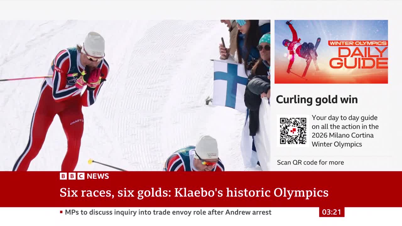 A cross-country skier in a red and blue suit leans forward, poles extended. Another skier is bent low on the snowy track behind him. A cross-country skier in a red and blue suit leans forward, poles extended. Another skier is bent low on the snowy track behind him.