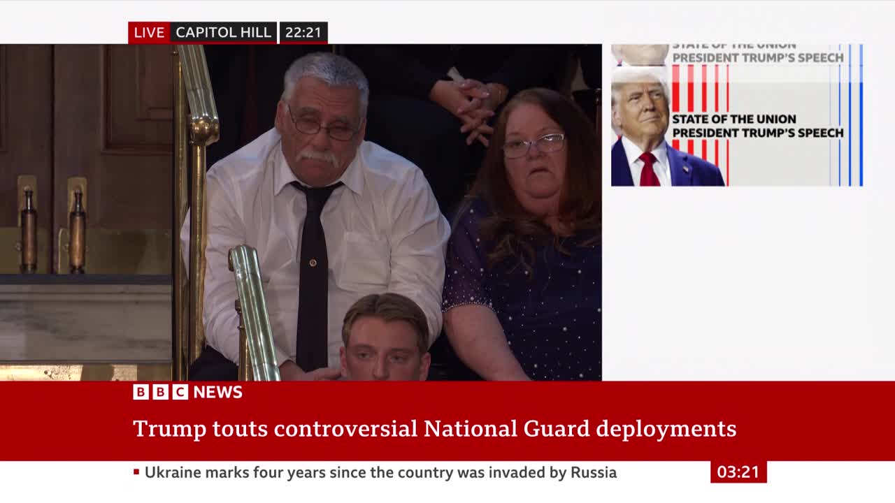 A man with a mustache and glasses sits next to a woman wearing a sparkly blue top, both looking towards something off-camera. A smaller inset on the right shows a picture of Donald Trump with text about his State of the Union speech. A man with a mustache and glasses sits next to a woman wearing a sparkly blue top, both looking towards something off-camera. A smaller inset on the right shows a picture of Donald Trump with text about his State of the Union speech.