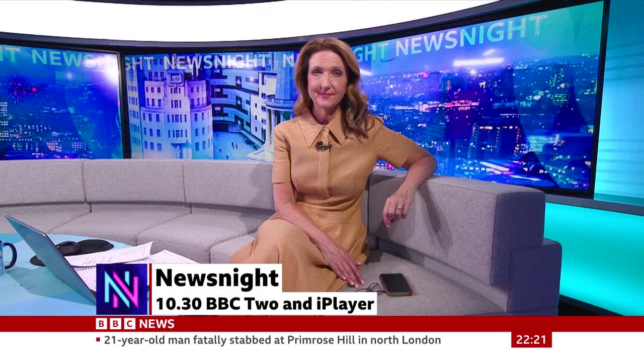 A woman in a tan dress sits on a grey sofa in front of a large screen displaying a city at night. The BBC Newsnight logo and broadcast details appear on a graphic in the foreground.