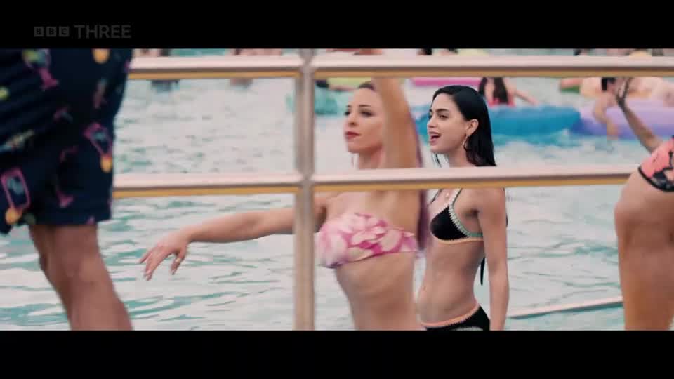 A woman in a floral bikini reaches out her arm as she stands in a pool. Beside her, another woman in a black bikini talks animatedly. A woman in a floral bikini reaches out her arm as she stands in a pool. Beside her, another woman in a black bikini talks animatedly.