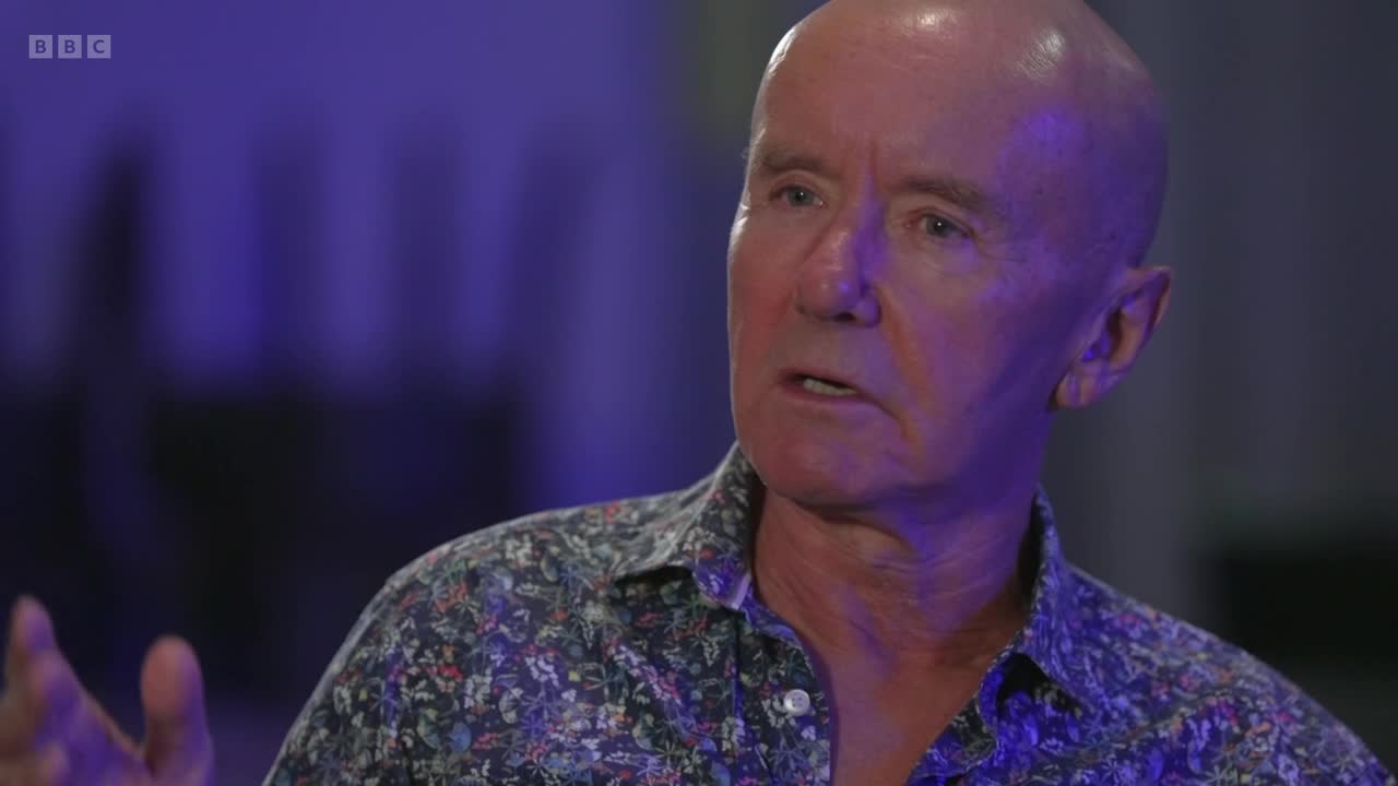 A man in a floral shirt is speaking, gesturing with his left hand. The BBC Two logo is visible in the corner.
