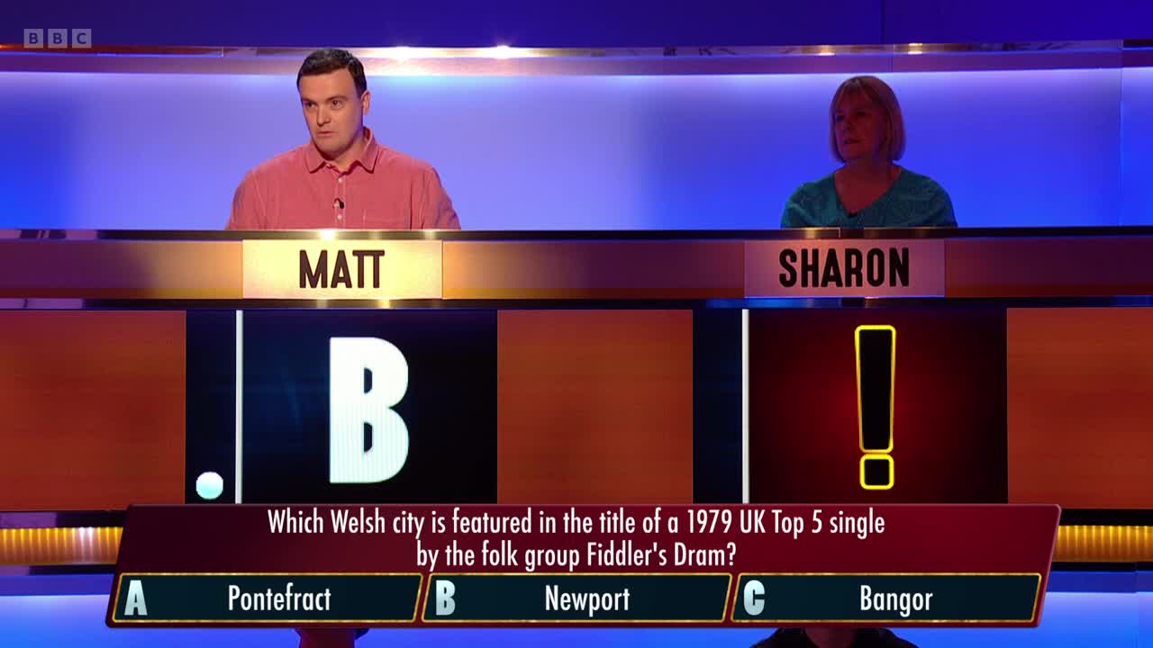 Matt and Sharon sit behind their podiums, facing the camera on BBC Two. A question about a Welsh city and a 1979 UK chart hit is displayed on the screen.

