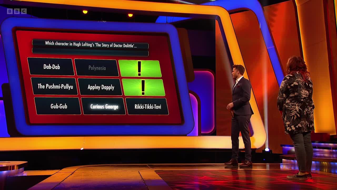 On BBC Two, the host, in a suit, stands to the left of a contestant. The game show's screen displays a question about a children's book, with some answers highlighted in green.
