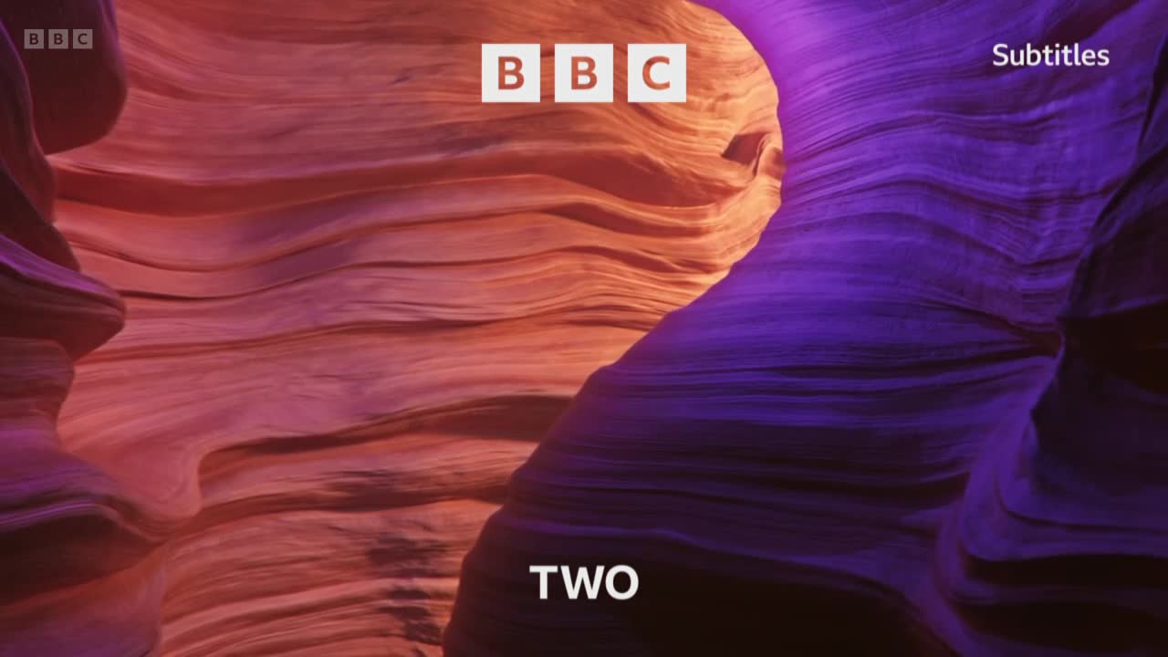 The BBC logo sits above the word "TWO" against a backdrop of swirling, textured rock formations. The left side is bathed in warm orange and red hues, while the right is a deep purple.
