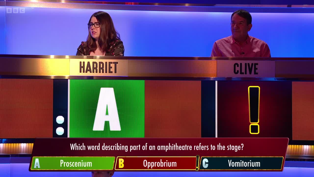 Harriet, in glasses, looks thoughtful, while Clive, in a pink shirt, appears to be waiting. A question about an amphitheater is displayed on the screen, with the answer choices highlighted.
