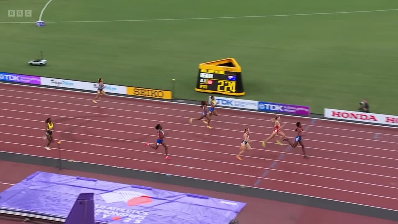 Runners are sprinting down the track, their legs pumping as they near the finish line. The scoreboard displays the time as the athletes push for the win.
