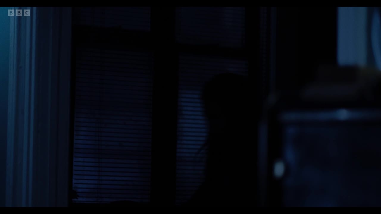 A person's silhouette is visible behind the blinds, their shape barely discernible in the dim light. The window's slats cast shadows across the room.
A person's silhouette is visible behind the blinds, their shape barely discernible in the dim light. The window's slats cast shadows across the room.
