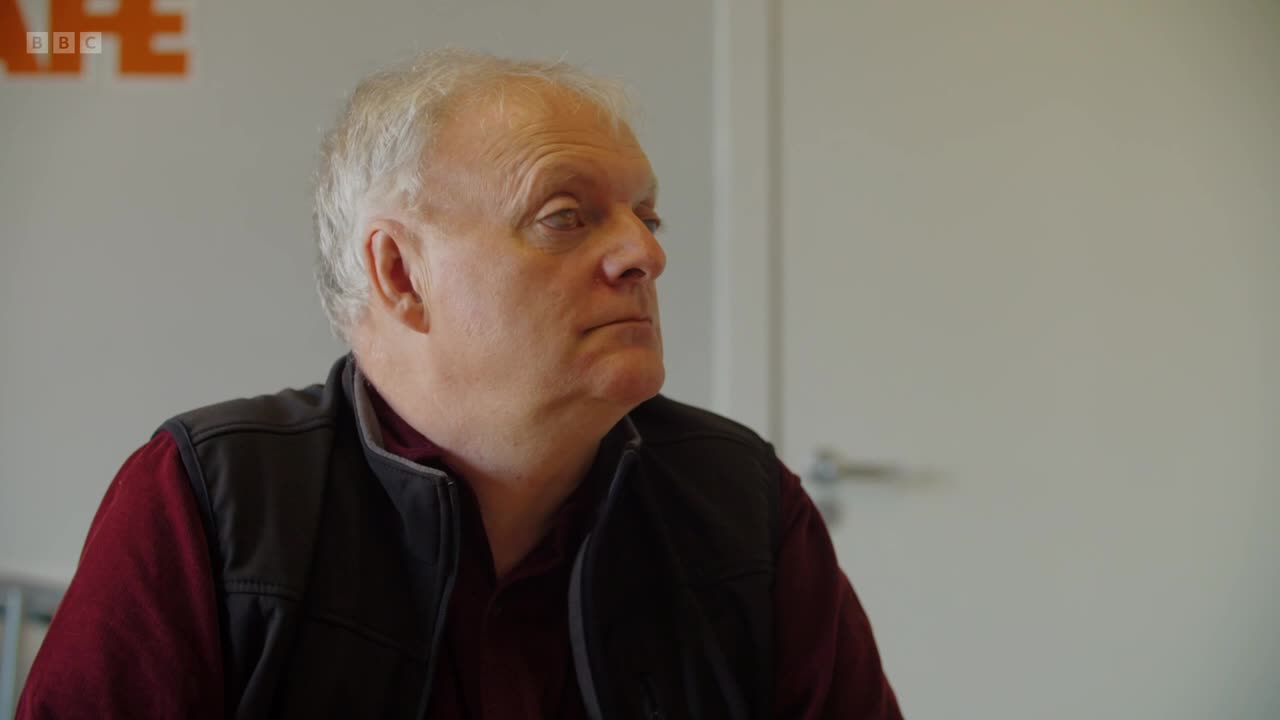 The man turns his head, his gaze fixed on something off-camera. A BBC Two logo is visible in the background.