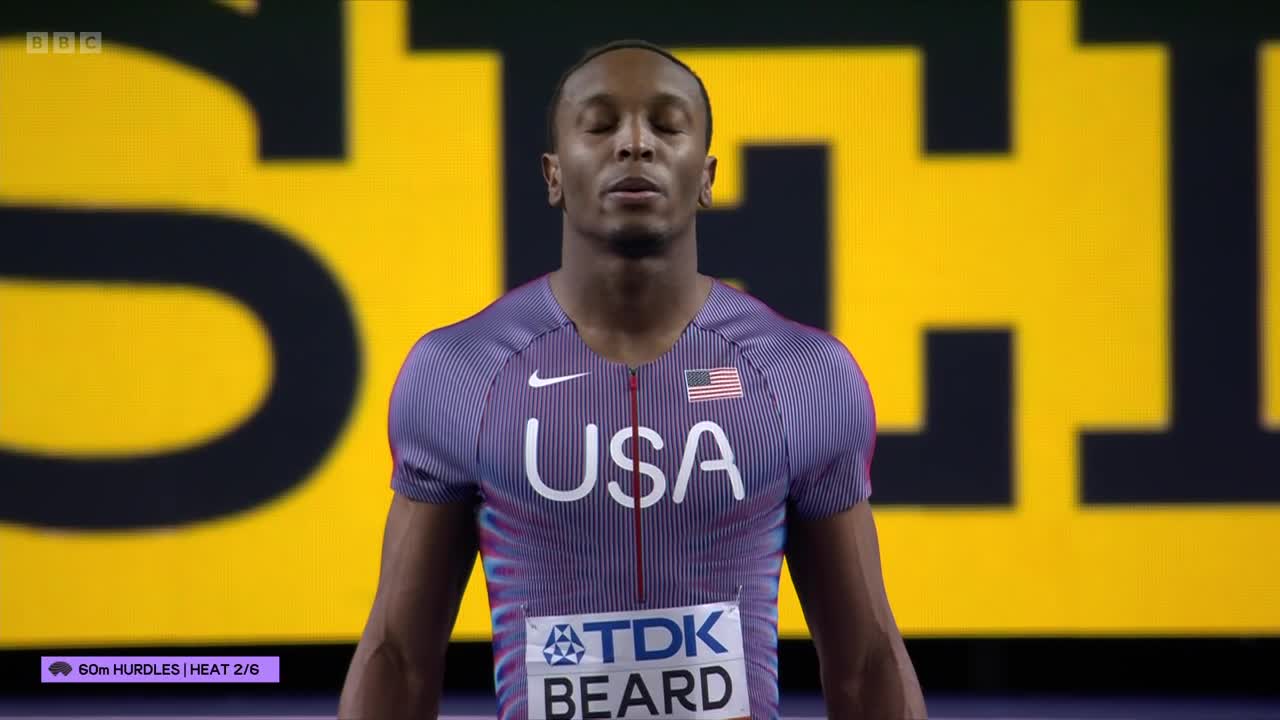 The athlete stands with his eyes closed, preparing for the 60m hurdles. The BBC Two broadcast shows his name, Beard, on his bib.