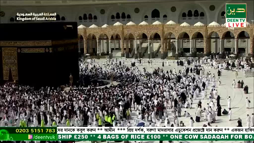 A dense crowd of people in white garments moves around a large, black cubic structure. The scene is being broadcast live on Deen TV from the Kingdom of Saudi Arabia.
