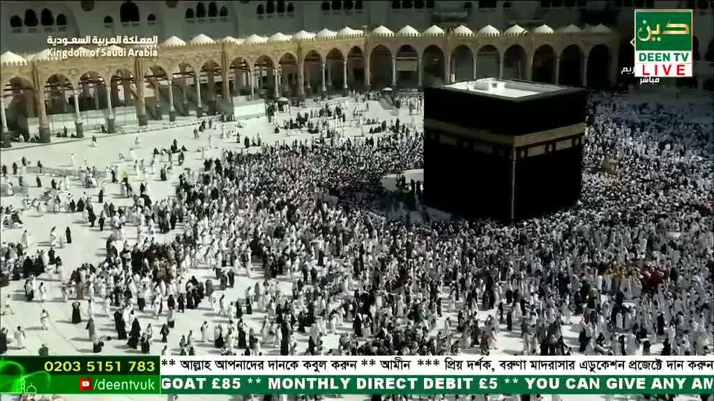A sea of people, mostly in white, flows around a large, black cube. The Deen TV logo is visible, broadcasting from the Kingdom of Saudi Arabia.
