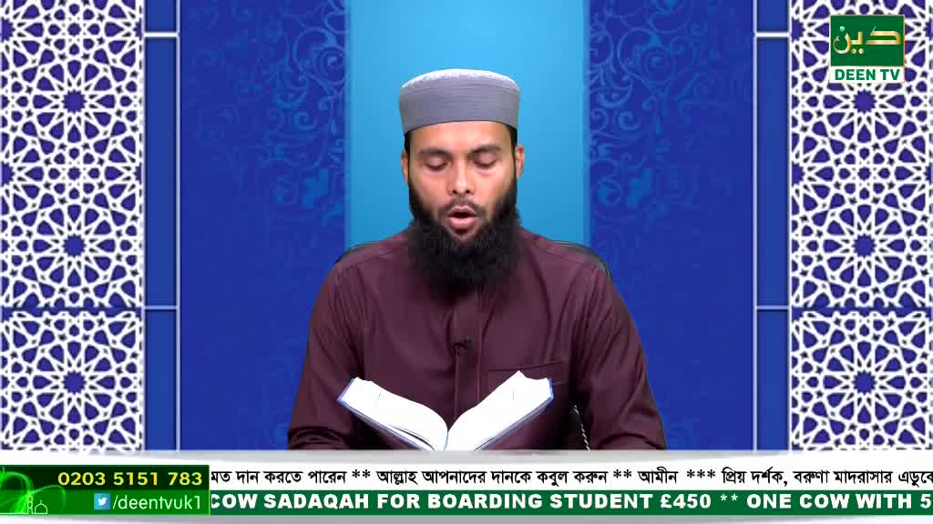 A man with a long, dark beard reads from an open book, his mouth moving as he speaks. He's on a Deen TV set in the United Kingdom, with a blue backdrop and geometric patterns on either side of him.
