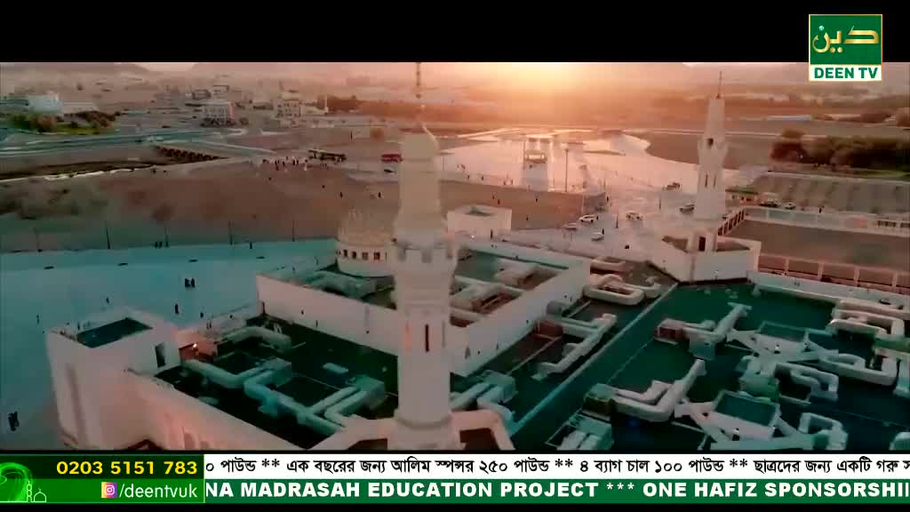 From this vantage, the white minarets and domes of a mosque rise against a hazy sky. Below, the rooftops and surrounding structures are bathed in the soft light of what looks like a Deen TV broadcast.
