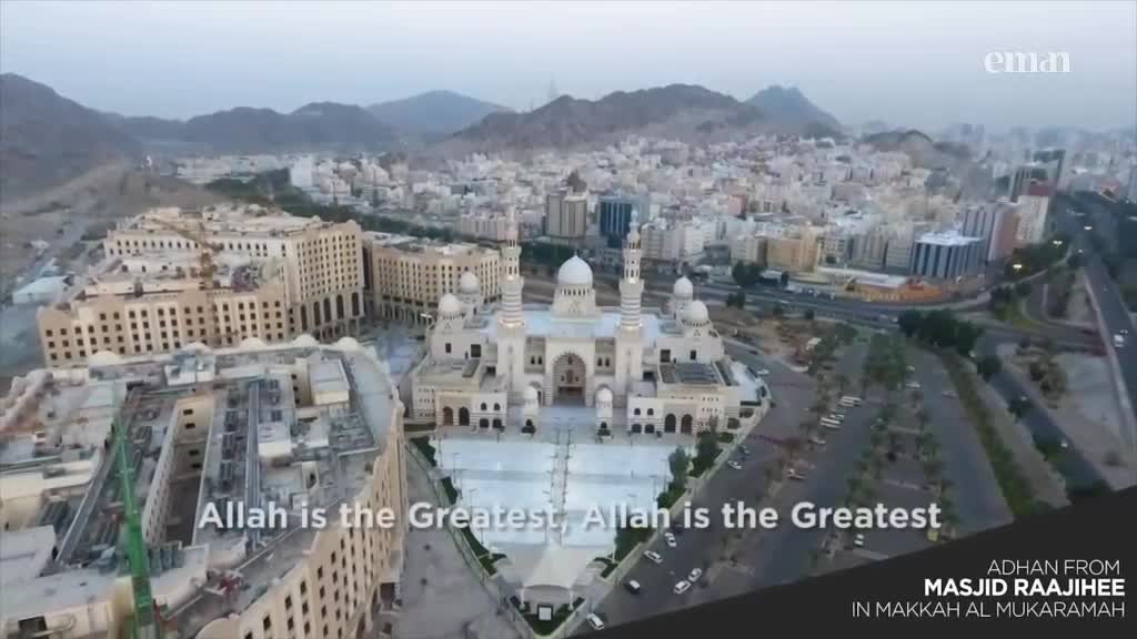 From this vantage point, a large mosque with white minarets stands out against the city backdrop. The Eman Channel logo is visible, and the adhan, "Allah is the Greatest," is displayed on the screen.

