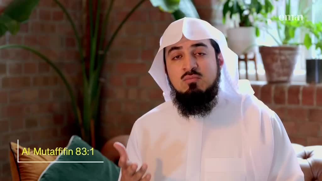 A man in a white robe and head covering gestures with his right hand. He's seated in what looks like a living room in the United Kingdom, likely filming for the Eman Channel.
