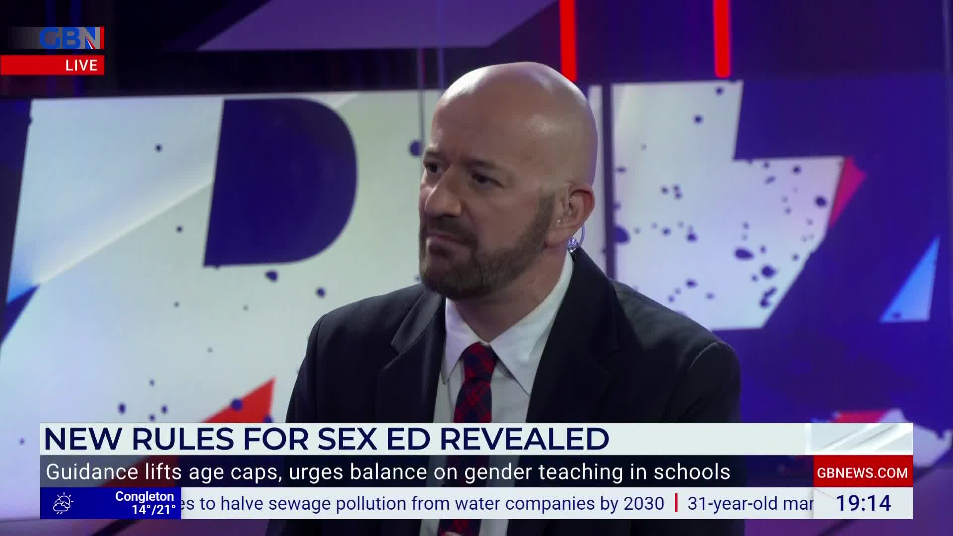 A man in a suit and tie is speaking, his gaze directed slightly off-camera on the GB News set. Beneath him, a headline about sex education in the UK is displayed.
