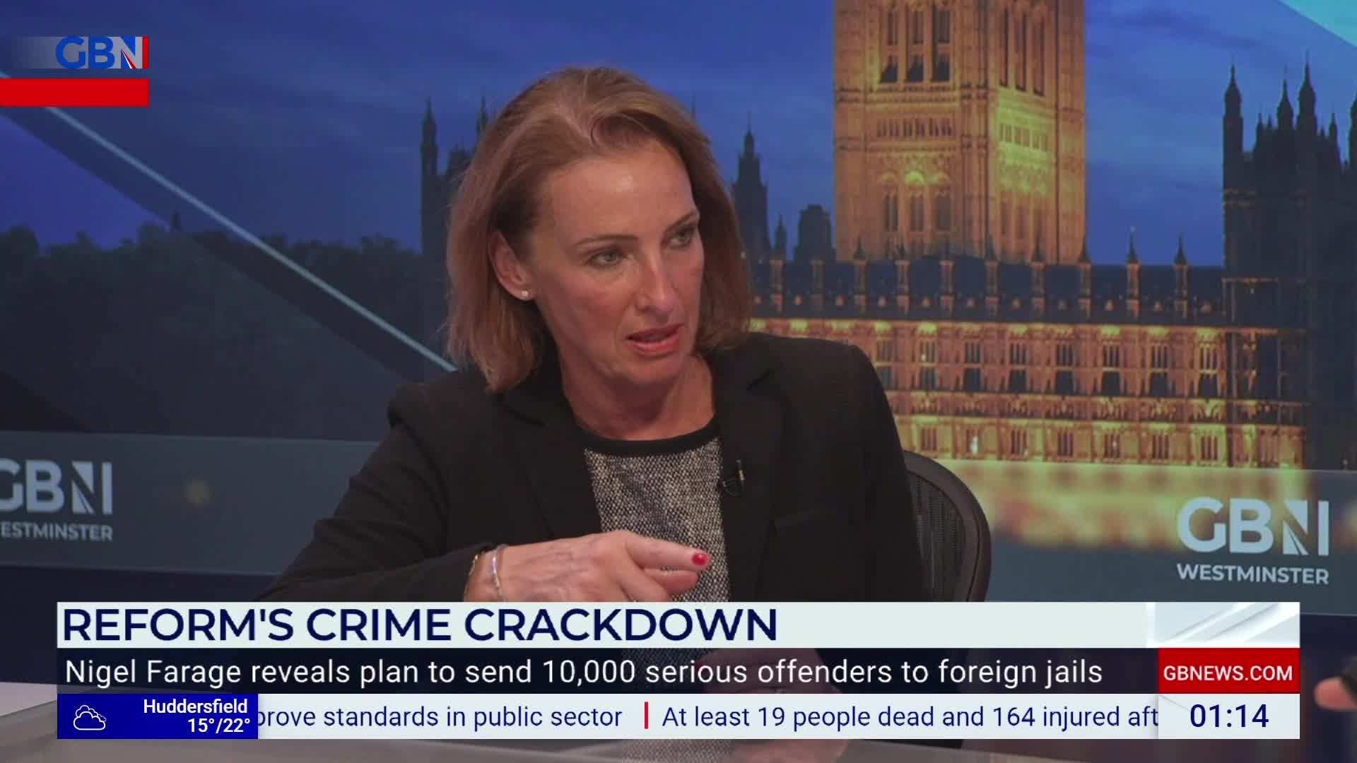 A woman in a blazer is speaking, gesturing with her right hand. Behind her, a backdrop shows the Houses of Parliament, and the GB News logo is visible.
