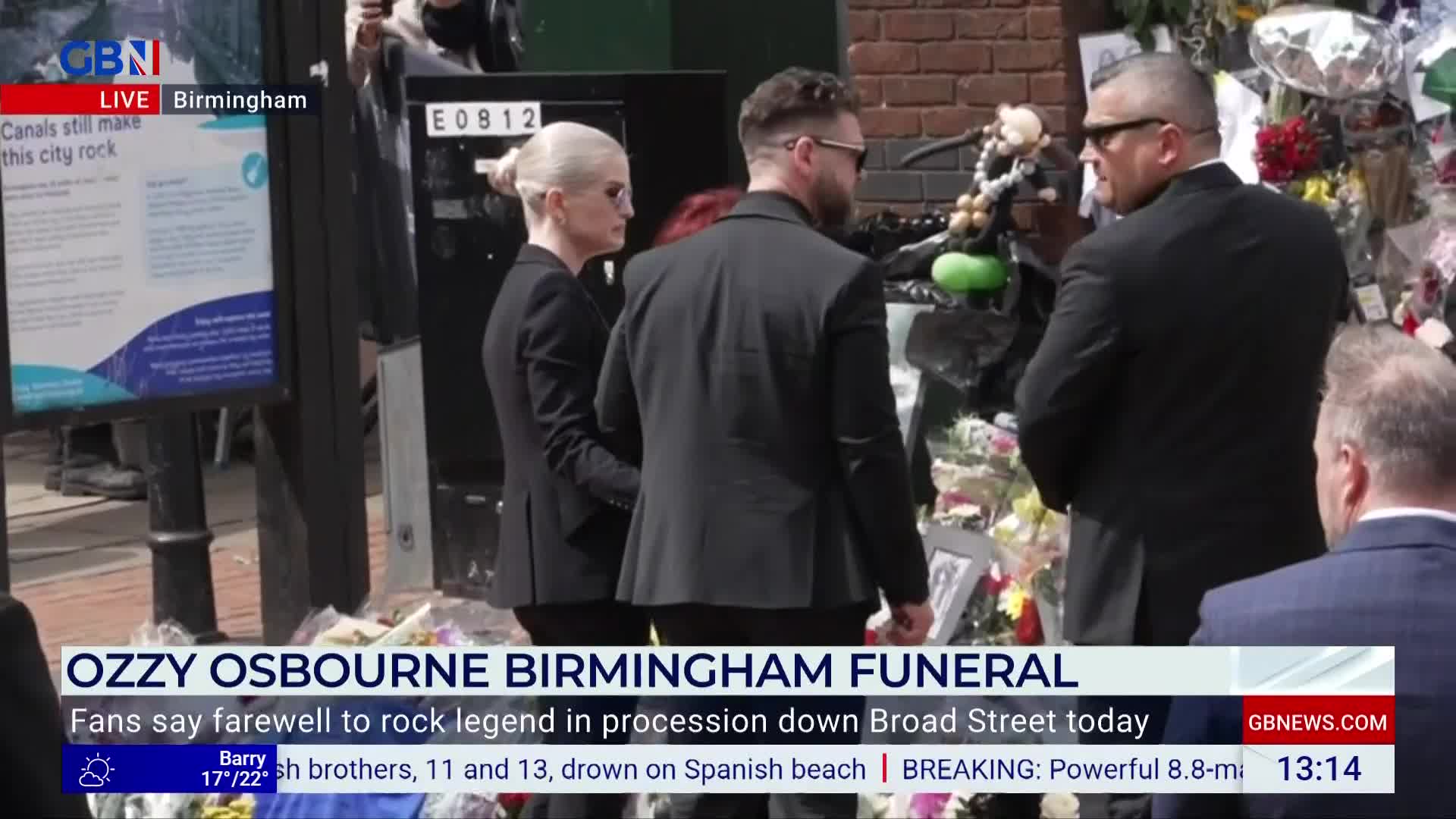 A small group, dressed in black, walks past a memorial of flowers. GB News is reporting live from Birmingham, where fans are paying their respects.
