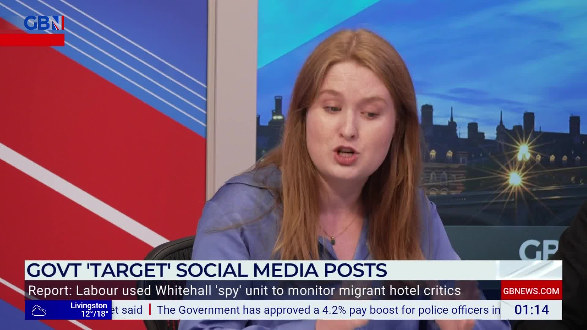 A woman with auburn hair is speaking animatedly on a GB News set. The screen behind her shows a city skyline, and the lower third banner announces a story about the government targeting social media posts.
