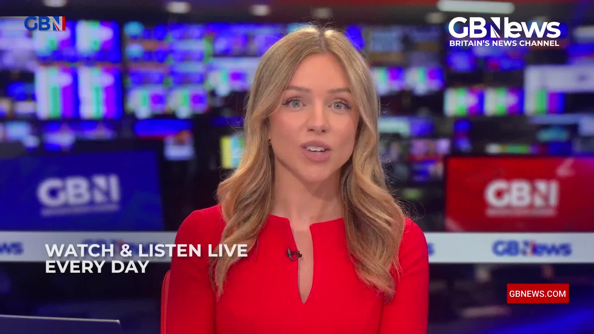 A woman in a red dress speaks directly to the camera, positioned in front of a backdrop of screens displaying the GB News logo. The words "Watch & Listen Live Every Day" are printed below her.
