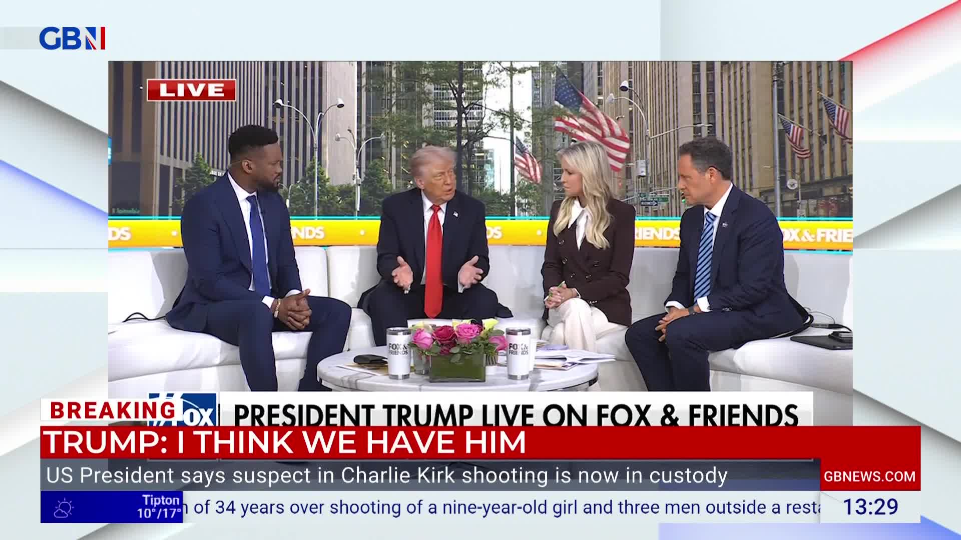 Four people sit on a white sofa, framed by a backdrop of American flags and city buildings. Donald Trump gestures with both hands while speaking, and the GB News graphic at the bottom of the screen highlights his appearance on Fox & Friends.
