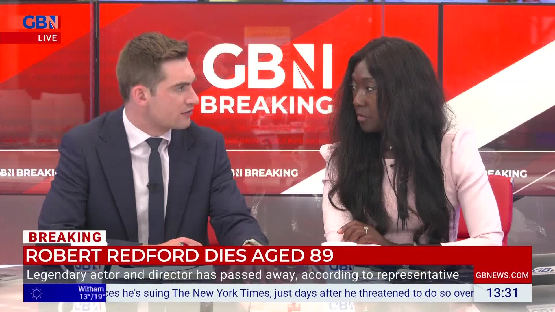 A man in a suit and tie gestures as he speaks, while a woman in a pink blazer listens intently. The GB News logo and "BREAKING" graphic are visible on the screen behind them.
