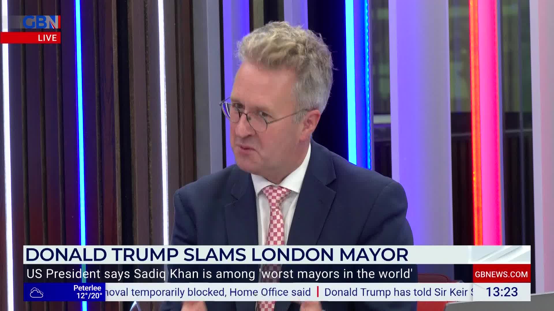 A man in a suit and tie is speaking on GB News, his expression intense. The lower third of the screen announces a story about Donald Trump criticizing the London Mayor.
