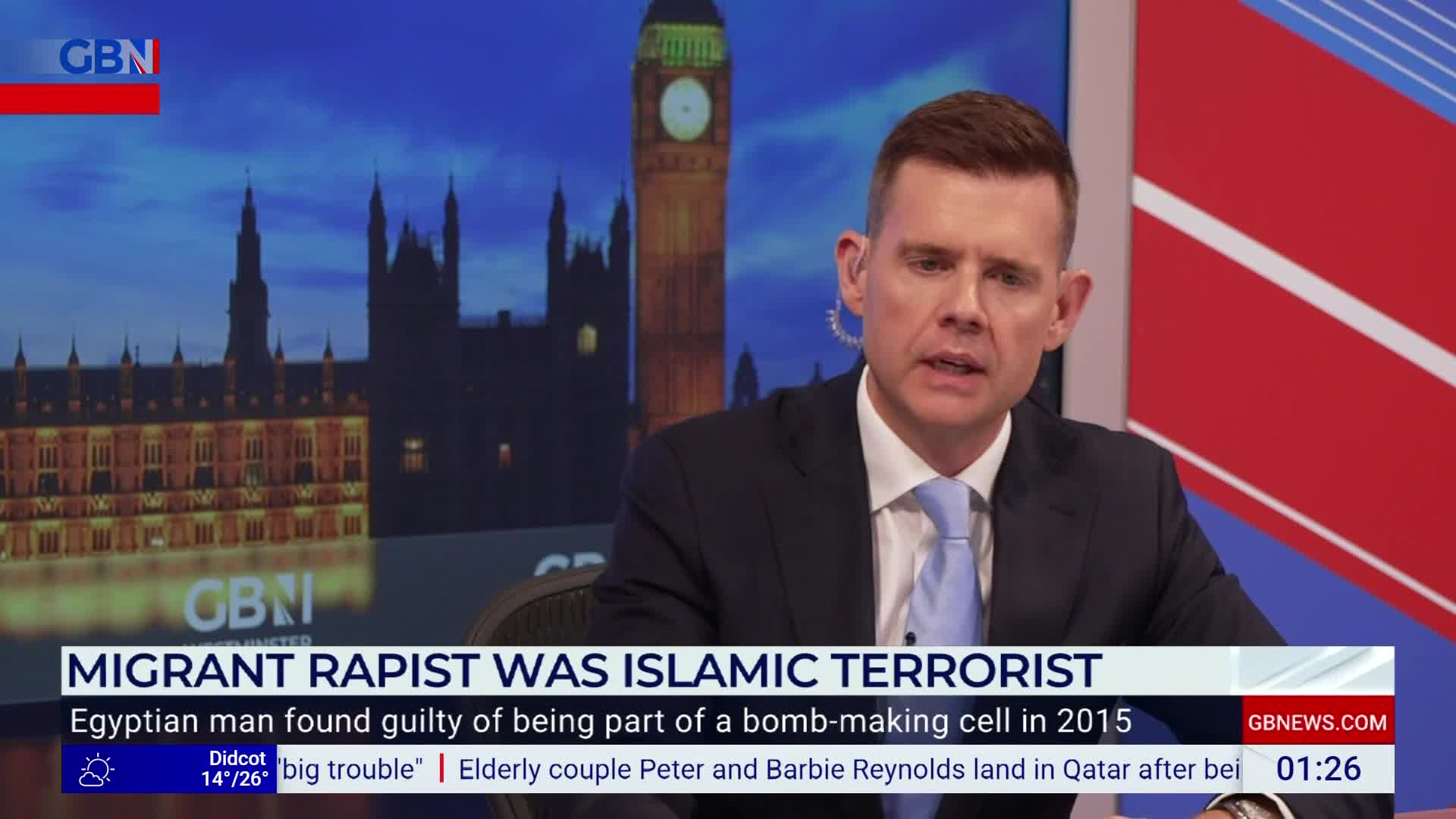 A man in a suit and tie speaks directly to the camera, with a backdrop of the Houses of Parliament. The GB News logo is visible, and a headline about a migrant rapist scrolls across the bottom of the screen.
