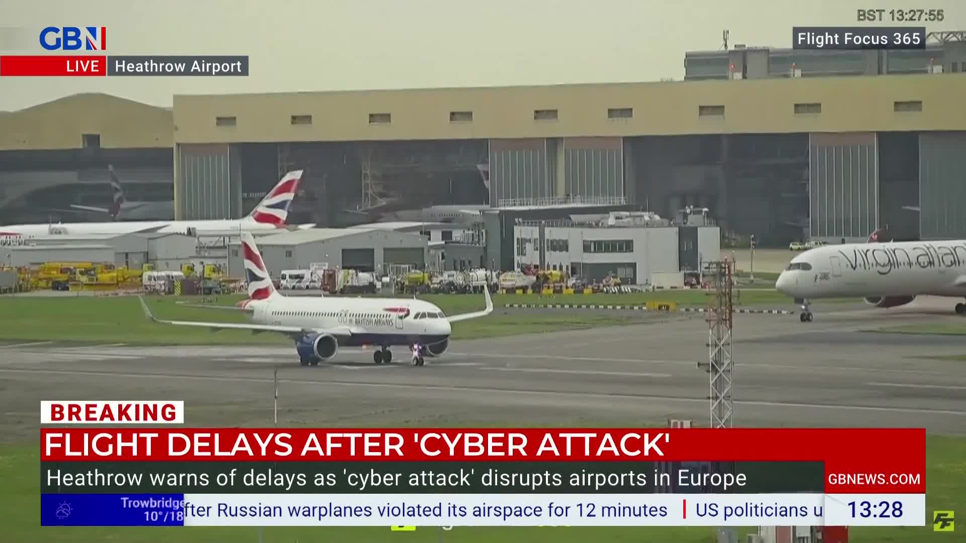 A British Airways plane is slowly moving across the tarmac at Heathrow. A Virgin Atlantic aircraft is visible in the distance as the GB News graphic flashes news of flight delays.

