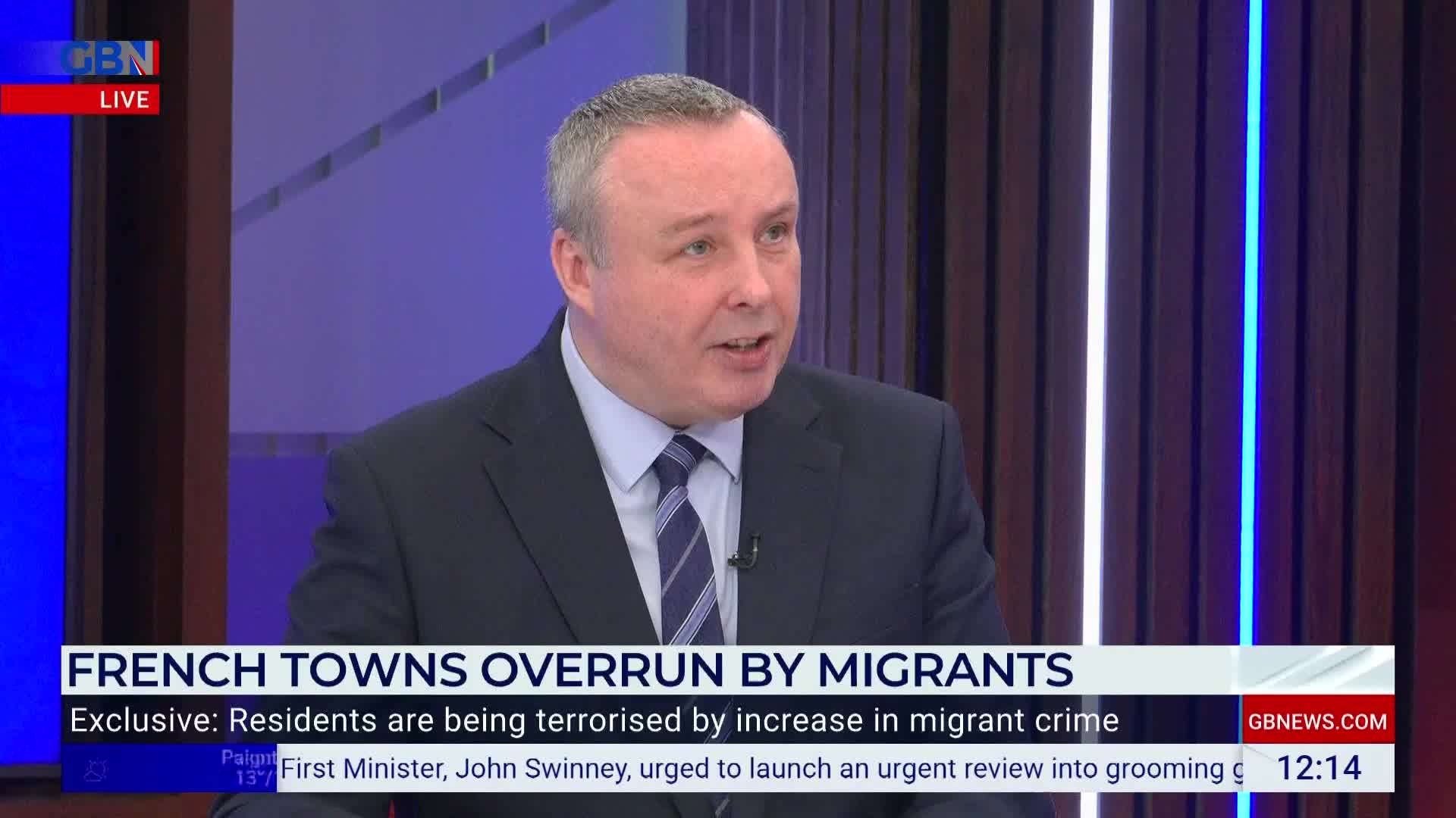 A man in a suit is speaking intently, his mouth moving as he addresses the camera on GB News. The chyron below highlights a story about French towns and migrants.
A man in a suit is speaking intently, his mouth moving as he addresses the camera on GB News. The chyron below highlights a story about French towns and migrants.