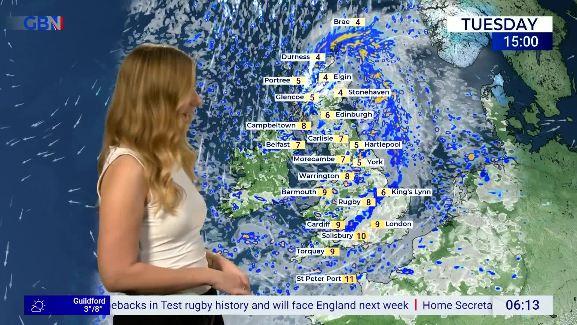 A woman stands beside a weather map of the United Kingdom, gesturing towards it as she speaks. The screen displays temperatures for various locations, with the GB News logo visible in the corner.
