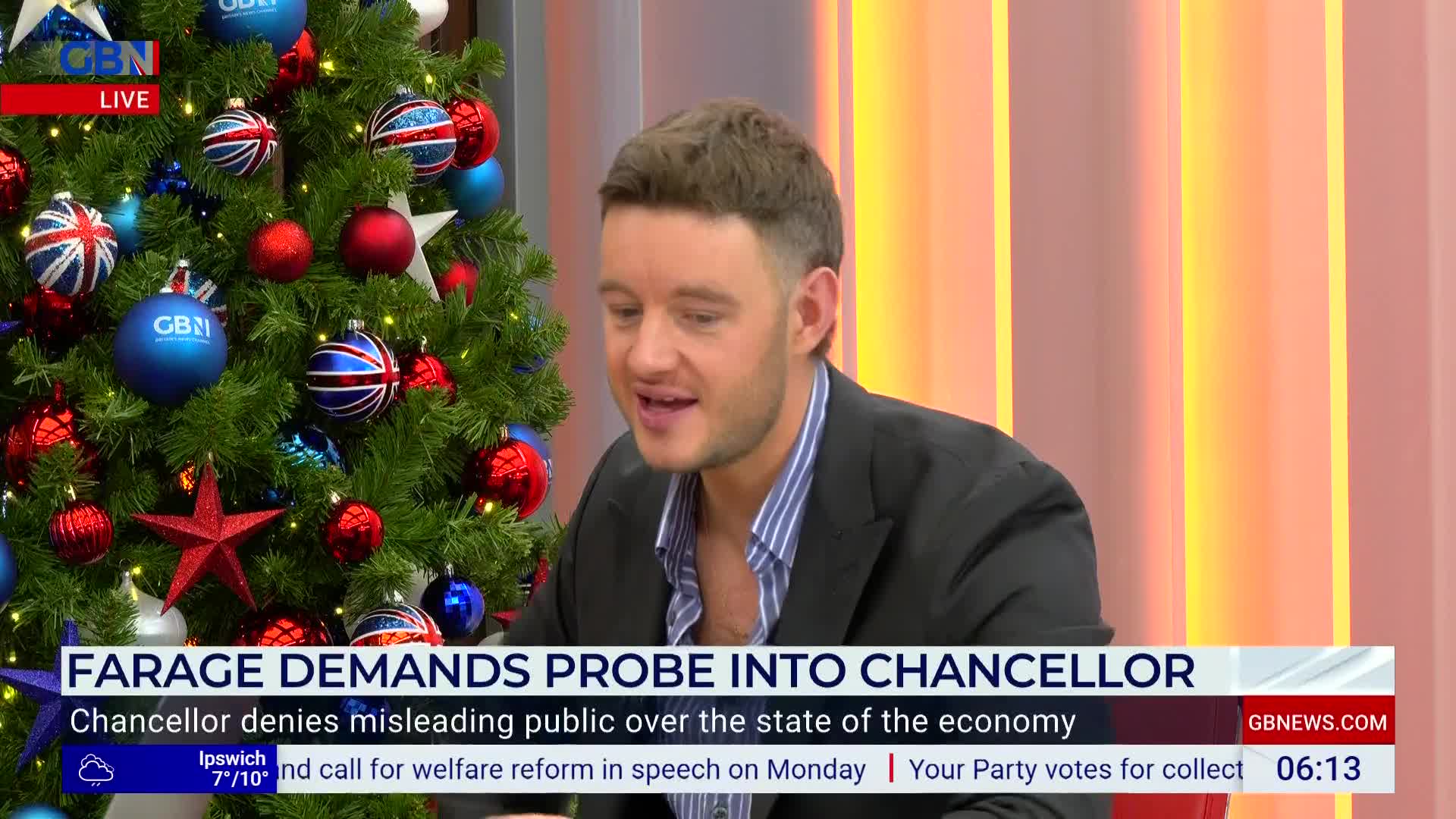 A man in a blazer is speaking on GB News, his face animated. Behind him, a Christmas tree decked with Union Jack ornaments and GB News logos adds a festive touch to the studio.
A man in a blazer is speaking on GB News, his face animated. Behind him, a Christmas tree decked with Union Jack ornaments and GB News logos adds a festive touch to the studio.