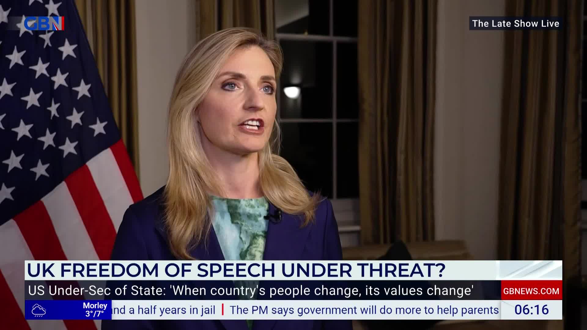 On GB News, a woman with blonde hair, wearing a blue blazer, is speaking with a serious expression. Behind her, the American flag hangs, and the lower third of the screen asks about freedom of speech in the United Kingdom.
On GB News, a woman with blonde hair, wearing a blue blazer, is speaking with a serious expression. Behind her, the American flag hangs, and the lower third of the screen asks about freedom of speech in the United Kingdom.