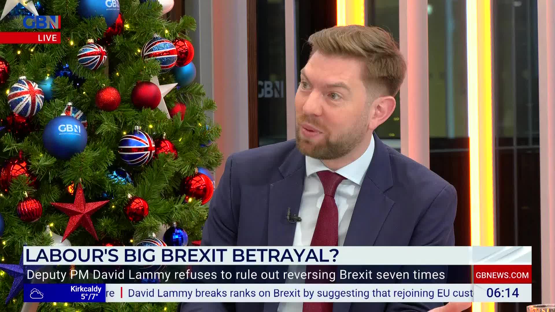 A man in a suit is speaking animatedly on a GB News set, with a Christmas tree decorated with Union Jack-themed ornaments beside him. The lower third of the screen displays a headline about Brexit and David Lammy.
A man in a suit is speaking animatedly on a GB News set, with a Christmas tree decorated with Union Jack-themed ornaments beside him. The lower third of the screen displays a headline about Brexit and David Lammy.