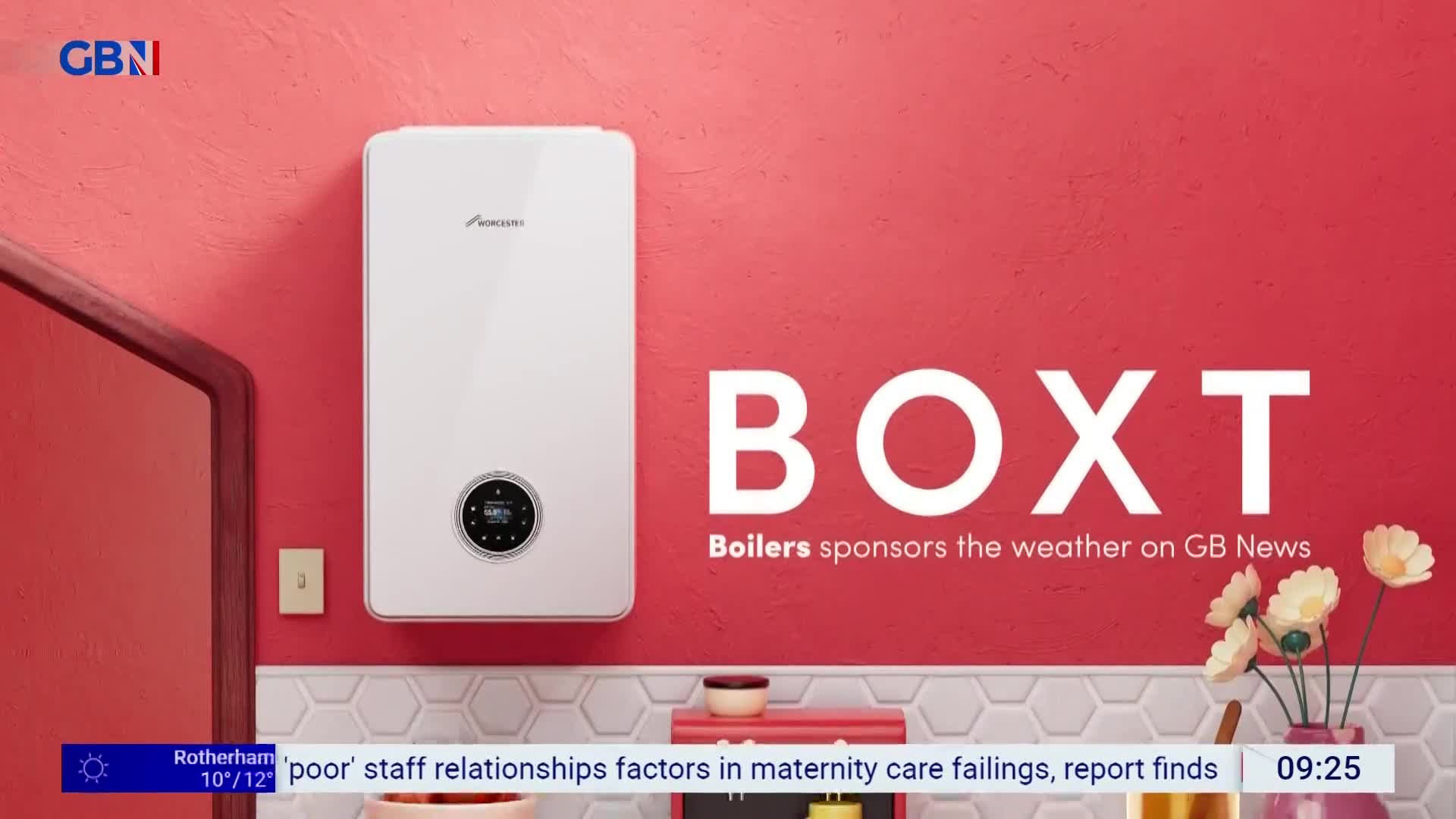 A white boiler hangs on a bright red wall, its digital display glowing. The large white letters spelling "BOXT" dominate the space next to it, with smaller text below stating "Boilers sponsors the weather on GB News."