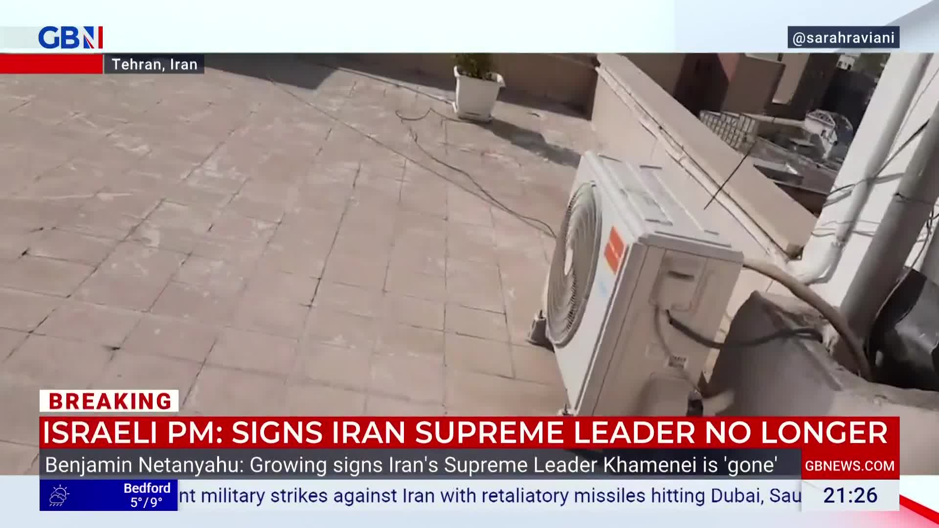 A white air conditioning unit sits on a tiled rooftop under a bright sky. A GB News chyron scrolls across the bottom of the screen, reporting on developments in Iran.