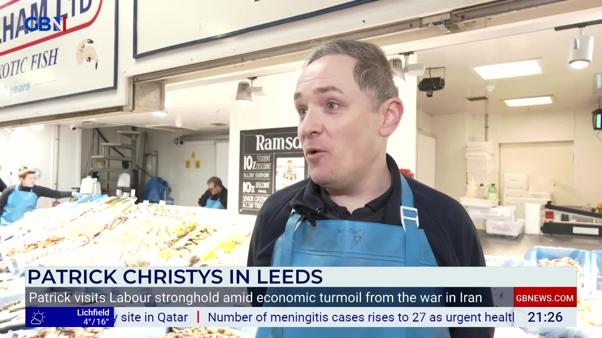 A man in a blue apron speaks to the camera. Behind him, a busy fish market in Leeds displays its wares. A man in a blue apron speaks to the camera. Behind him, a busy fish market in Leeds displays its wares.