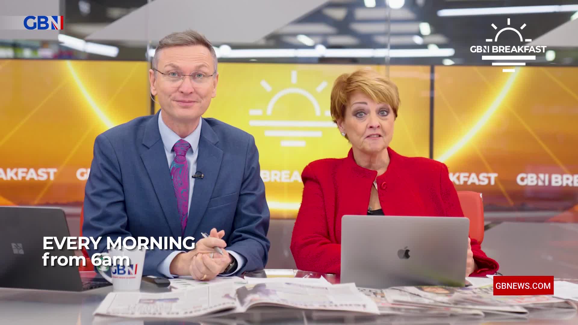 A man in a suit and a woman in a red jacket sit at a desk, both looking towards the camera. Behind them, a large screen displays the GB News Breakfast logo and text that reads "EVERY MORNING from 6am." A man in a suit and a woman in a red jacket sit at a desk, both looking towards the camera. Behind them, a large screen displays the GB News Breakfast logo and text that reads "EVERY MORNING from 6am."