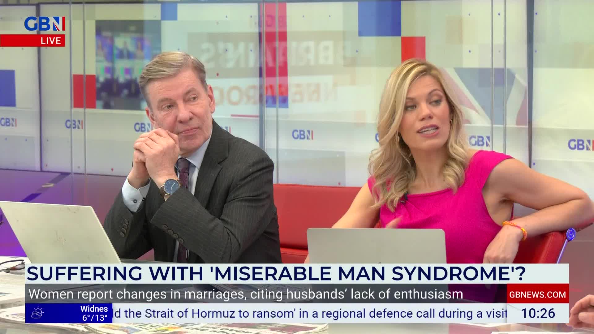 A man in a suit leans forward, his hands clasped, listening intently. Beside him, a woman in a bright pink dress speaks, her expression animated. A man in a suit leans forward, his hands clasped, listening intently. Beside him, a woman in a bright pink dress speaks, her expression animated.