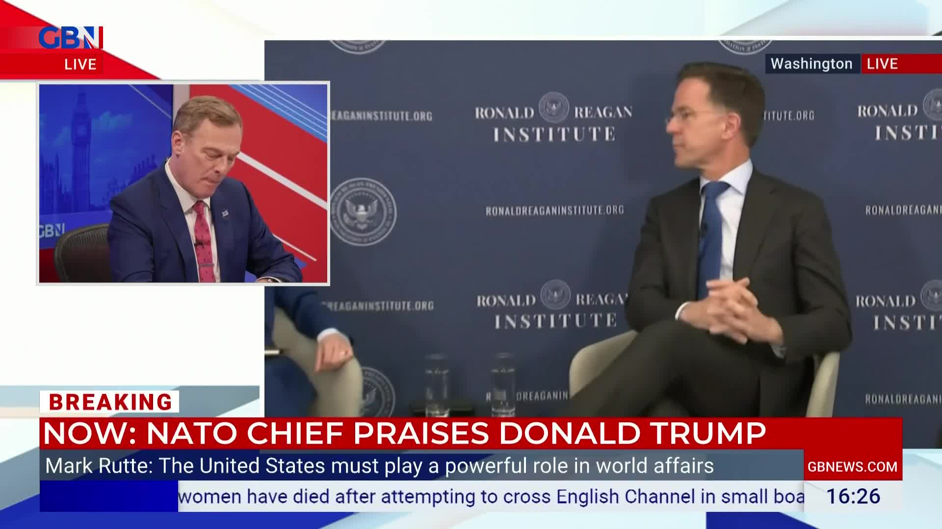 A man in a dark suit and blue tie leans forward, hands clasped, speaking at an event in Washington. On a smaller screen, a man in a blue suit and red tie looks down, a backdrop of Big Ben visible behind him. A man in a dark suit and blue tie leans forward, hands clasped, speaking at an event in Washington. On a smaller screen, a man in a blue suit and red tie looks down, a backdrop of Big Ben visible behind him.