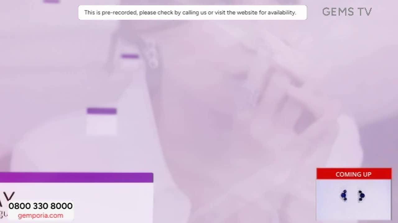 A blurred image of a person is on screen, with a "pre-recorded" message from Gems TV at the top. Below, a phone number and website are displayed, along with a "Coming Up" graphic.
