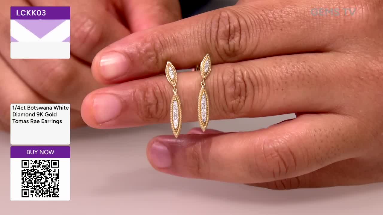 A pair of gold earrings, each with a diamond-studded teardrop shape, hangs between two hands. The jewelry is presented against a plain background, likely on a Gems TV broadcast from the United Kingdom.
