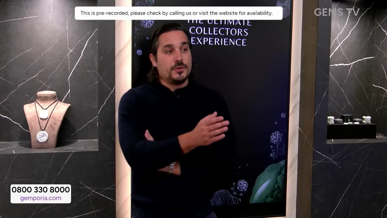 A man in a dark sweater gestures while speaking on a Gems TV set. Behind him, a display shows jewelry and a screen promoting "The Ultimate Collectors Experience."
A man in a dark sweater gestures while speaking on a Gems TV set. Behind him, a display shows jewelry and a screen promoting "The Ultimate Collectors Experience."