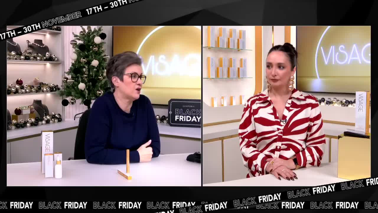 The woman in the blue sweater gestures toward a product on the table, while the other woman in the red and white shirt listens intently. A small Christmas tree sits behind the first woman, and the words "Black Friday" are displayed across the bottom of the screen.
The woman in the blue sweater gestures toward a product on the table, while the other woman in the red and white shirt listens intently. A small Christmas tree sits behind the first woman, and the words "Black Friday" are displayed across the bottom of the screen.
