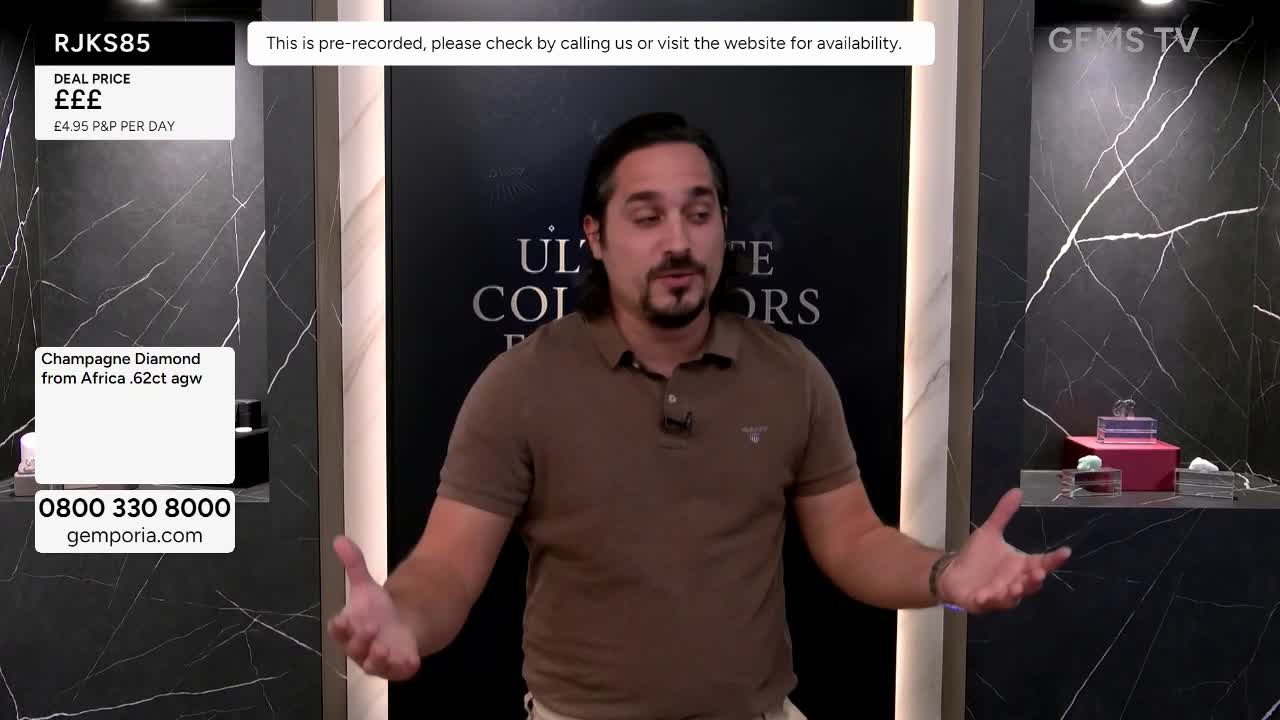 The man on Gems TV gestures with open hands, talking to the camera. Behind him, the background is a sleek black and white, with a display of jewelry.
