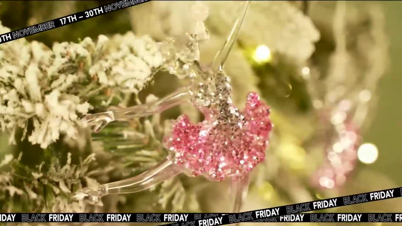 A delicate, clear plastic ballerina ornament, with a pink glittery tutu, hangs on a snowy Christmas tree. The words "Black Friday" are printed on a black banner across the bottom of the screen, likely a promotion on Gems TV in the United Kingdom.
